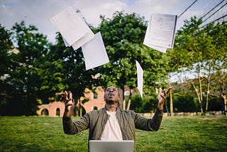 A man joyfully tossing resume papers in the air after getting a job, creating a playful mess.