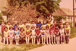 A teacher and her second grader students pose for a photo outside in front of the school.