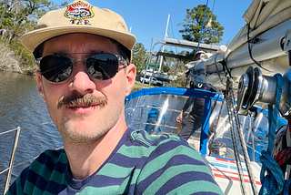 Author with partner in the background sailing boat away from harbor