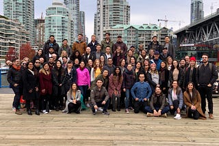 Team Thinkific poses on a dock at Vancouver’s Granville Island on a cloudy day during a quarterly team wide celebration.