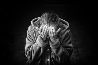 Black and white image of a person covering their face.