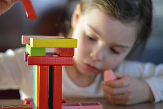 A little girl stacks toy blocks