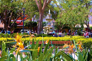 A bustling urban square in Antigua with fountains, flowers, and benches