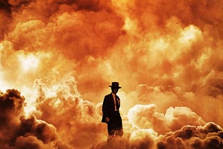 A small silhouette of Cillian Murphy as Dr. Oppenheimer, wearing his suit and hat, against the backdrop of a larger atomic explosion.