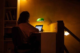 Woman sitting in low lighting in front of a tablet, working