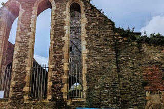 Ruins of Greyfriars Church in Waterford, Ireland, with colorful trash bins in the foreground.