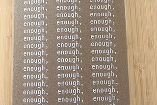 Book with cardboard cover, word ‘enough’ printed repeatedly filling up the whole cover