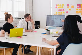 A group of 4 UX designers collaborating around a table in an office.