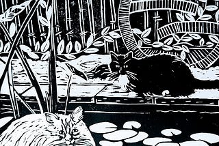 Black and white lino print of two cats by a pond, one is a white rag doll, the other a black and white “tuxedo” cat. There are water lily pads and foliage and a circle garden ornament that is vaguely asian, the fence behind then is bamboo.
