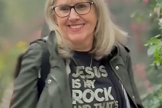 Photo of woman smiling and wearing a shirt that says, “Jesus is my Rock”