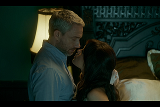 Martin Freeman as Jonathan Miller and Jenna Ortega as Cairo Sweet standing close together, almost kissing, in “Miller’s Girl”.