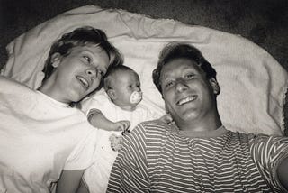 First time parents, Julie and Eric, pose with their newborn son.