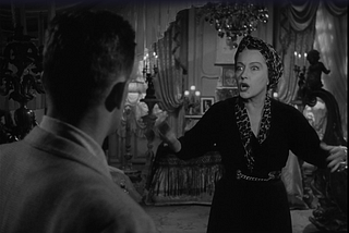 A shot from Sunset Boulevard in which Norma Desmond is talking and gesticulating while Joe Gillis is obscured by shadows