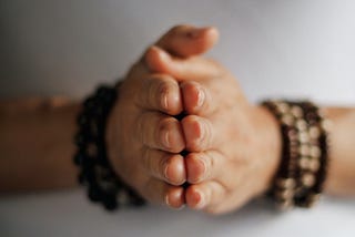 Woman’s hands with palms together practicing meditation or praying indoors.
