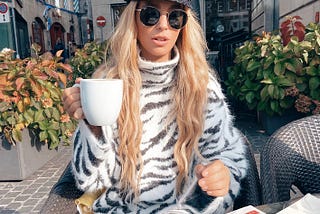 a woman sipping coffee in switzerland wearing animal print dress