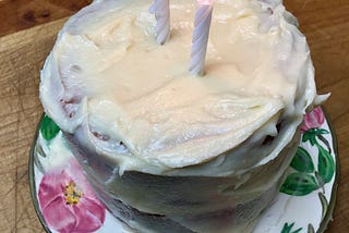 A small frosted cake with two lit candles