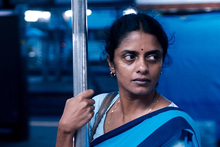 A woman in a blue sari holds a support in train