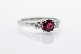 A ring with a purplish-red center stone.