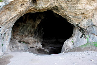 A photo of a cave entrance leading into the darkness.