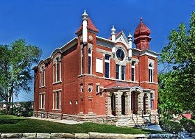 A photo of the ornate Jewish temple, Temple Aaron, which was founded in 1883 in Trinidad, Colorado. It’s red brick, with two turrets and a big clock at the front. Large stone pillars frame the entrance.