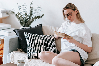 Focused woman reading book on sofa
