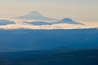 Photo of the mountains near the Cook Inlet in Alaska. Layers of blue-toned mountains with clouds lying low between them. Copyright 2024 David L. O’Hara, Ph.D.