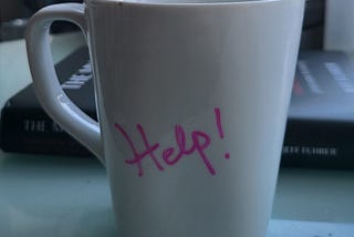 White mug with the words Help written in pink script