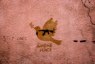 A red walk featuring a shadow of a bird with a gun on it. Under the bird are the words “imagine peace.”