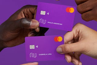 Mãos segurando cartões do Nubank