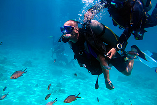 2 scuba divers diving in havelock Island surrounded by fishlife and other groups of divers