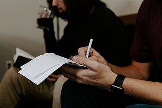 A man writing on a notepad in a cafe.