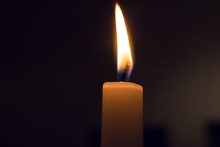 Single candle burning on black background
