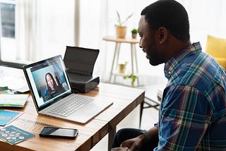 A person conducting an interview with another person remotely on a laptop