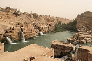 An image of an ancient hydraulic water system in Shushtar, Iran. The picture shows stone constructions with water flowing into a central dam.