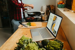 Image of someone cooking and following computerized instructions.