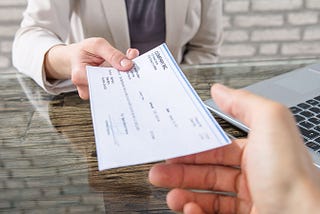 A employer handing an employee a paper check