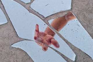Hand reflection in broken glass shards