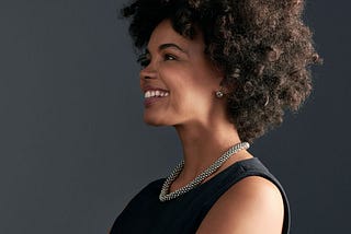 smiling professional woman in a black dress and silver necklace