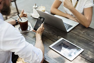 Two people meeting with laptops, tablets and phones