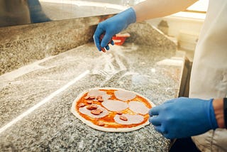 Person making pizza wearing nitrile gloves