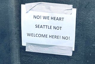 A sign printed on white paper saying No! We Heart Seattle not welcome here! No!