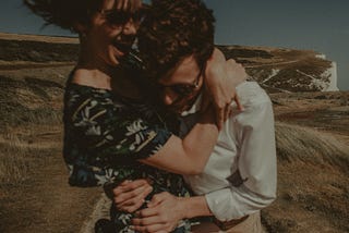 A happy couple embraces in a grassy field