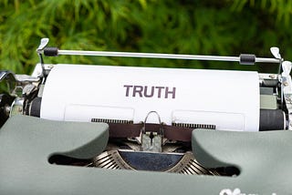 Antique typewriter holding one piece of paper, which says truth