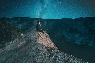 Person sitting on a rock looking out over a mountain range