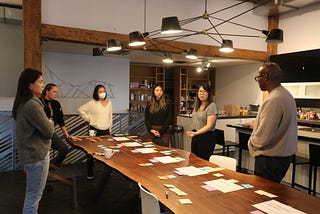 Members of the Openbox Design team discussing an early prototype timeline laid out on the studio’s dining table