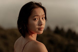 Young Asian-American woman in golden sun on mountainside