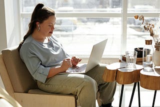 Woman sitting on a sofa while using a laptop.