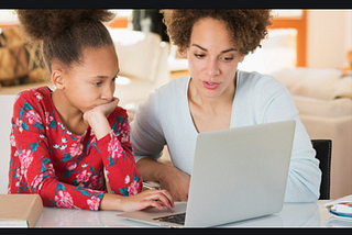 A mother guarding her ward looking at a screen while learning