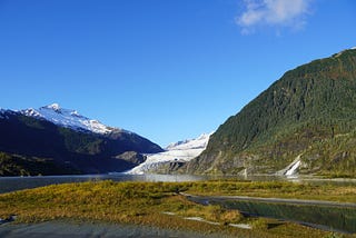 Scenic photo of Mendenhall Glacier in Juneau Alaska, nestled between mountains in a late Alaskan summer