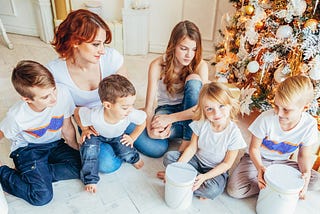 mother and five children relax playing near christmas tree on christmas eve at home